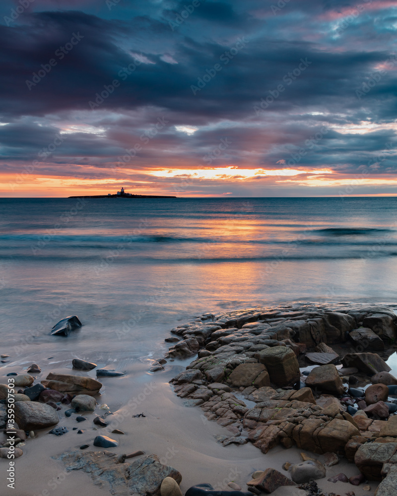 Sunrise at Hauxley Beach on the coast of Northumberland, England UK, with Coquet Island in the distance.