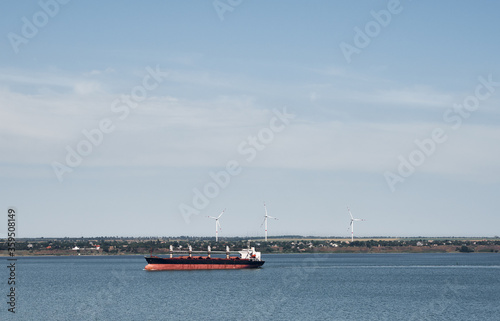 Obraz na plátně Commercial freight shipping vessel in front of wind mills