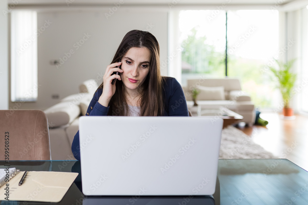 Young woman working from home, using mobile phone and laptop at the desk. Online meeting concept. Young woman working from home, using mobile phone and laptop at the desk. Online meeting concept.