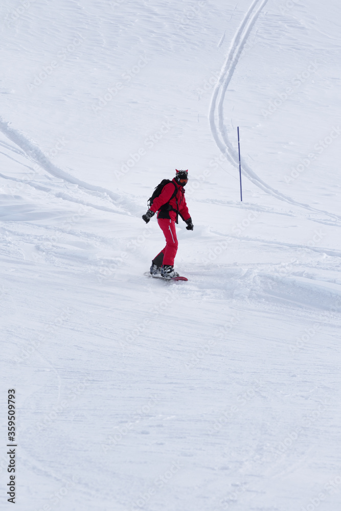 Snowboarder in red descends on snowy ski slope