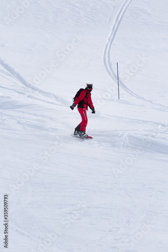 Snowboarder in red descends on snowy ski slope