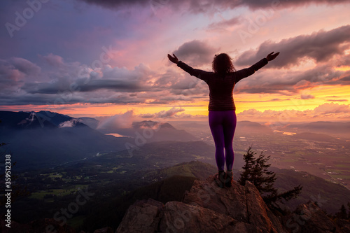 Adventurous Girl on top of a Rocky Mountain overlooking the beautiful Canadian Nature Landscape during a dramatic Sunset. Taken in Chilliwack, East of Vancouver, British Columbia, Canada.