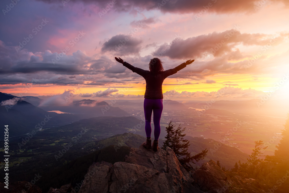 Adventurous Girl on top of a Rocky Mountain overlooking the beautiful Canadian Nature Landscape during a dramatic Sunset. Taken in Chilliwack, East of Vancouver, British Columbia, Canada.