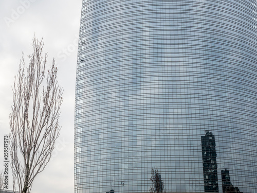 Fachade acristalada de un edificio moderno de oficinas con arblos sin hojas en primer plano photo