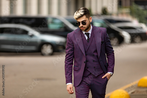 man in glasses and violet luxery three-piece suit, bow tie posing on the street © Volodymyr Shcerbak