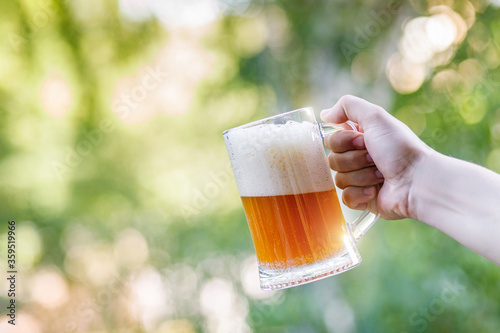 Glass of homemade beer in hand .