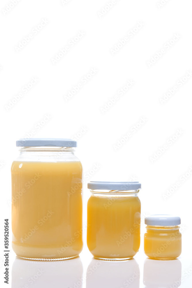 Glass jar with ghee butter over white background. Nutrition concept - Healthy food, Diet, Detox, Clean Eating or Vegetarian concept. Glass jar with ghee butter over white background. Nutrition concept - Healthy food, Diet, Detox, Clean Eating or Vegetarian concept.