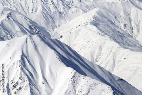 High mountains with sunlit snowy slope at cold winter day