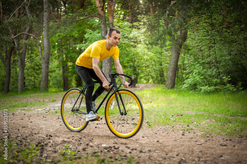 Portrait of a young man moving on a Bicycle. In a public Park, among trees and vegetation. © Evgeny Leontiev