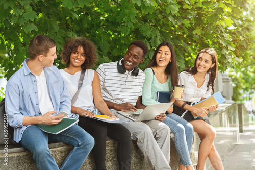 Group of multicultural students sitting in the university courtyard, studying together