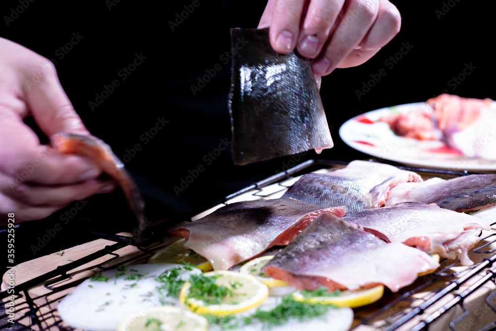the cook puts pieces of delicious red fish on the grill with onions and lemon and herbs