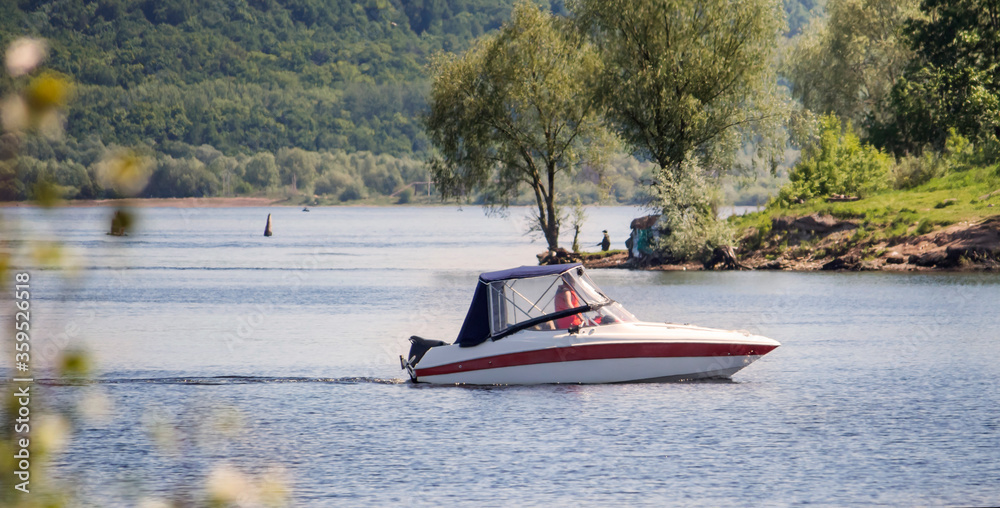 Fototapeta premium a boat with a motor floats along the river to the shore