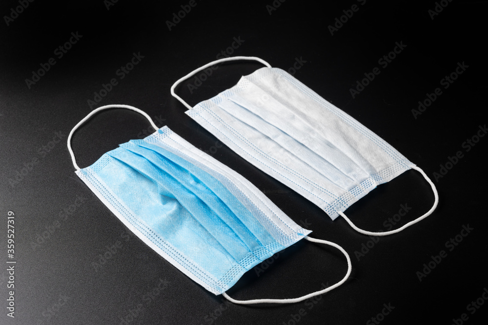Two side of Blue Medical mask with rubber ear straps. Typical 3-ply surgical mask on black background, Corona virus protection concept. Healthcare medical COVID-19 pandemic quarantine. Two side of Blue Medical mask with rubber ear straps. Typical 3-ply surgical mask on black background, Corona virus protection concept. Healthcare medical COVID-19 pandemic quarantine.