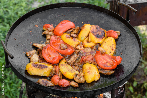 Fresh vegetables are cooked in a grill pan on open fire