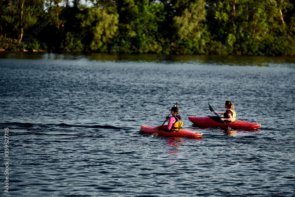 Two girls in a canoe-polo helmet rowing with weights and swimming on water. canupolo. in the rescue yellows. rear view.