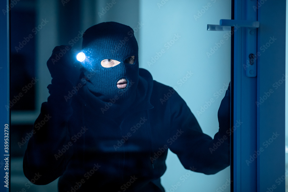 Intruder breaking in apartment or office using flash light