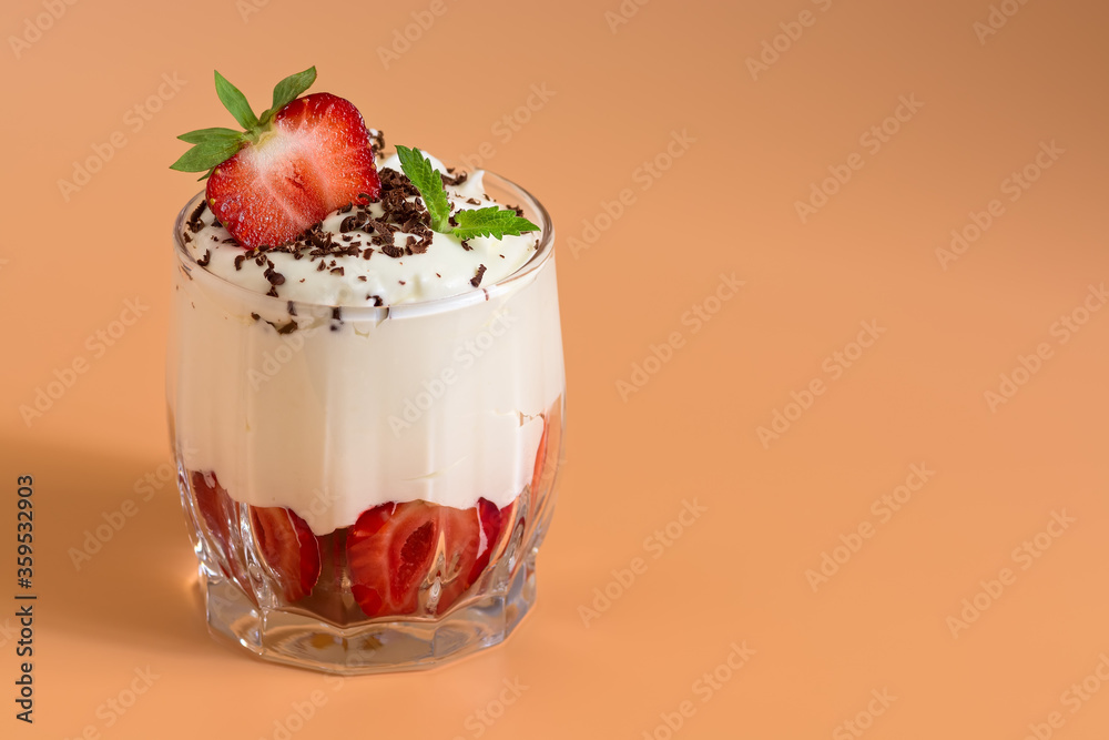 Fresh strawberry dessert with whipped cream in a glass on a pastel pink background. Selective focus, space for text. Fresh strawberry dessert with whipped cream in a glass on a pastel pink background. Selective focus, space for text.