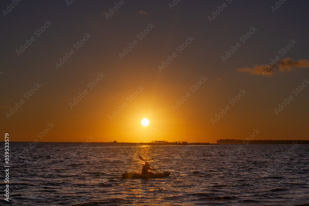 Person kayaking in the middle of the sea during sunset