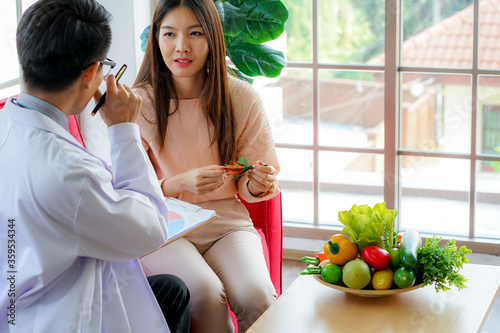 Asian medical doctor advised young female patient on  nutrition and healthy diet eating to prevent virus pandemic in clinical hospital. Doctor and patient concept. medicine and health care concept.
