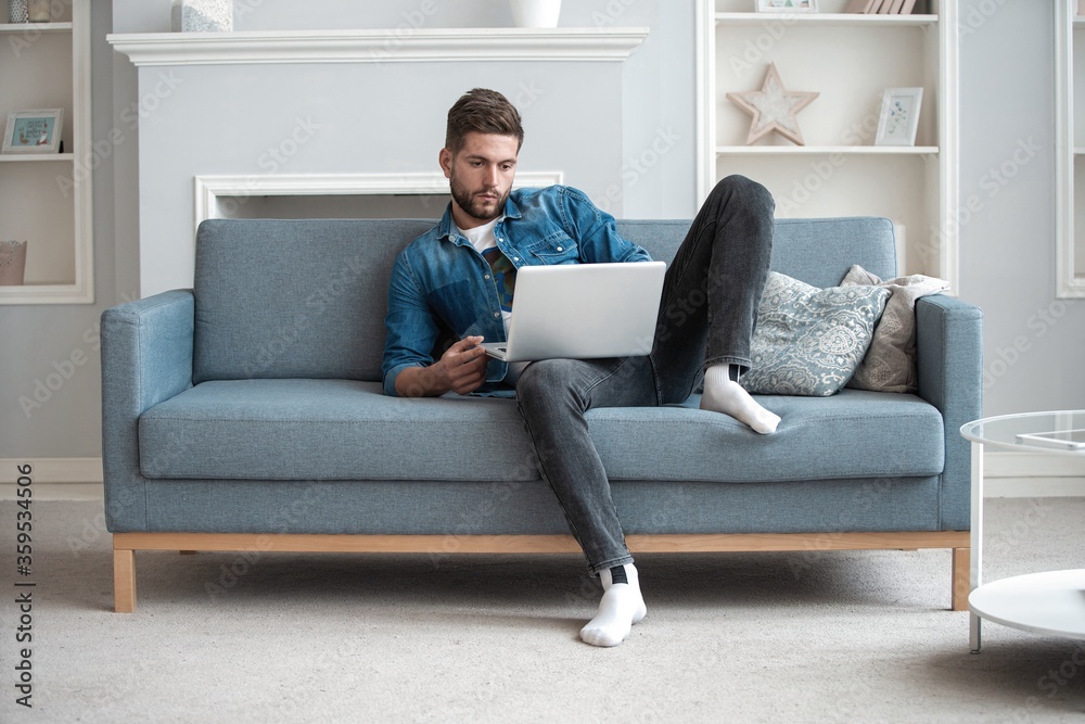 Handsome modern man designer working on laptop online, using internet at home Handsome modern man designer working on laptop online, using internet at home