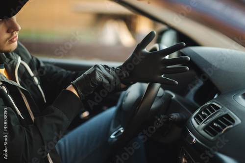 Man in car put on black gloves to protect himself