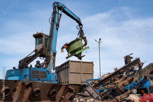 An excavator with a grab at work at a scrap metal dump.