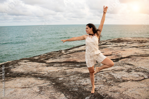 Photography Girl dancing ballet on a rock on the beach, blue sky near sunset, blue ocean in