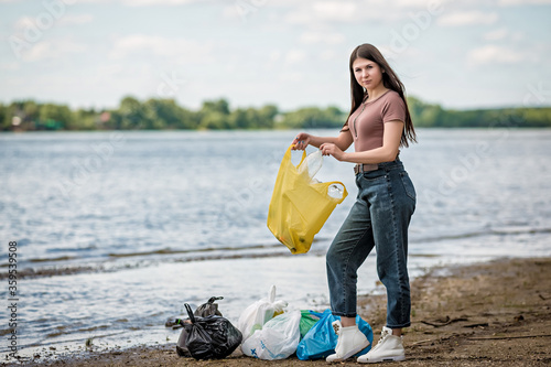 girl collects trash on the beach. girl cleans the beach of garbage