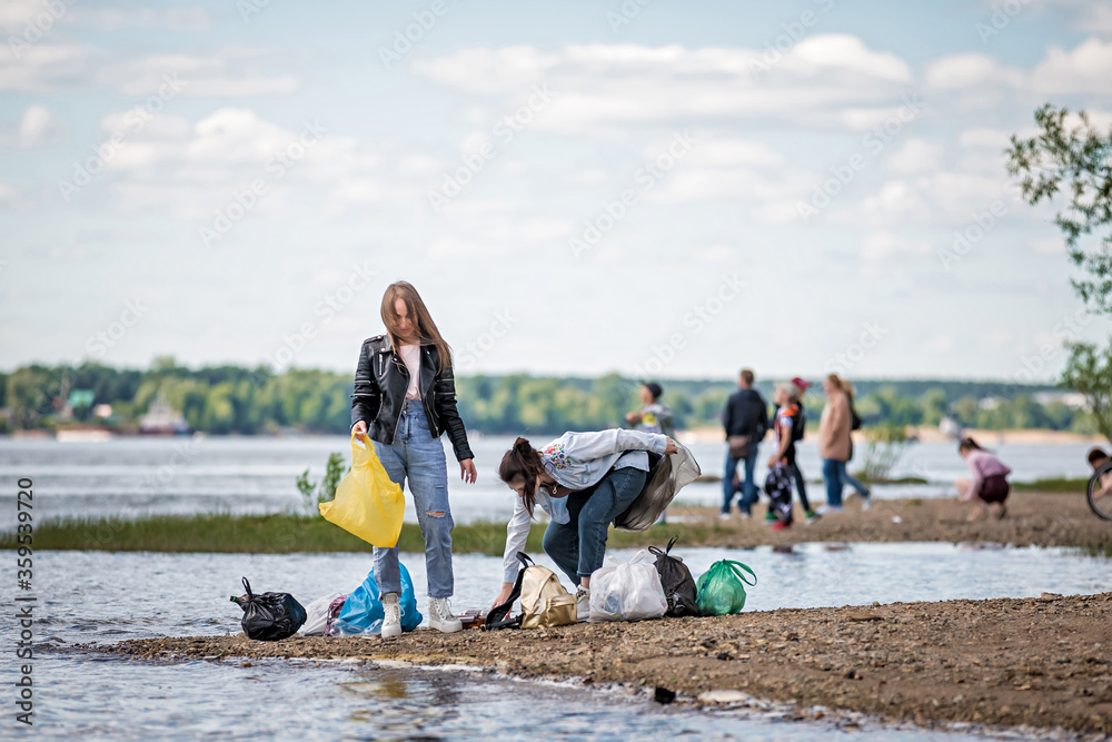 girls with trash on the beach. girls collect garbage on the beach. environmental concern girls with trash on the beach. girls collect garbage on the beach. environmental concern