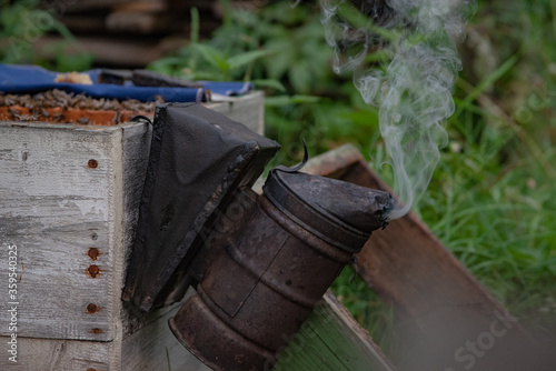 An old smoking smoker. A smoker hangs on the hive’s body and smokes. An old smoker.