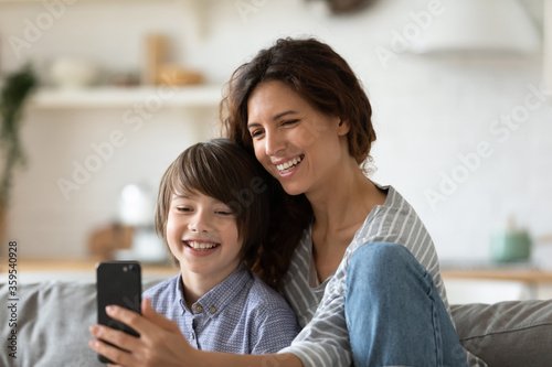 Close up happy young mother taking selfie with preschool son. Smiling attractive mom holding smartphone posing for photo with child. Family having fun together with modern mobile device.