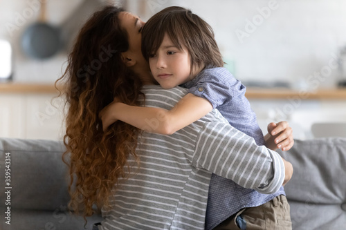 Close up caring young mother hugging preschool upset son. Lovely mom embracing and supporting child in difficult times. Stressful kid asking help from mum. photo