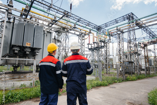 Two specialist electrical substation engineers inspect modern high-voltage equipment. Energy. Industry photo