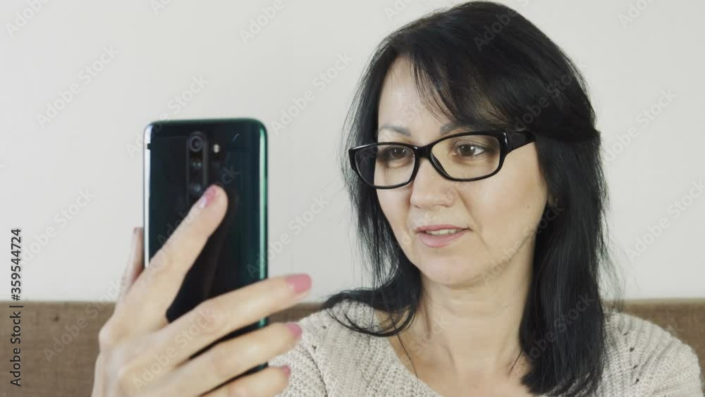 Pretty woman making selfie using mobile phone at home, office. Woman using smartphone on couch. Pretty woman making selfie using mobile phone at home, office. Woman using smartphone on couch.