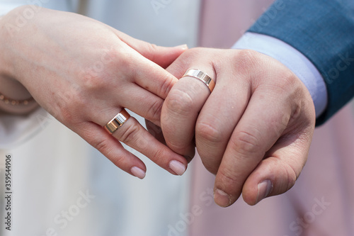  Hands of the newlyweds close-up with rings.