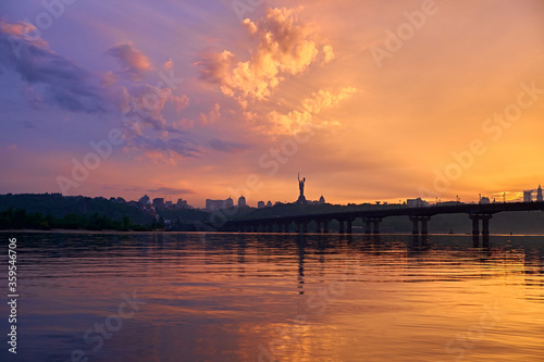 Orange blue sunset on the Dnieper river in Kyiv. Panorama of the bridge. Clouds in the sky. © Pihuliak