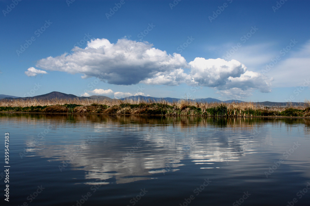 Lake scene in Montana with reflections of dynamic blue skies with clouds