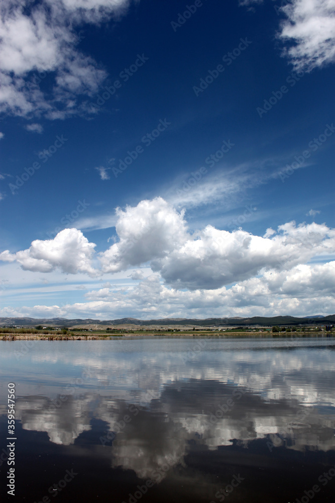 Obraz premium Lake scene in Montana with reflections of dynamic blue skies with clouds