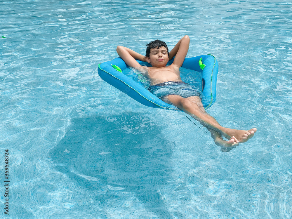 young boy in the pool in summer relaxing 