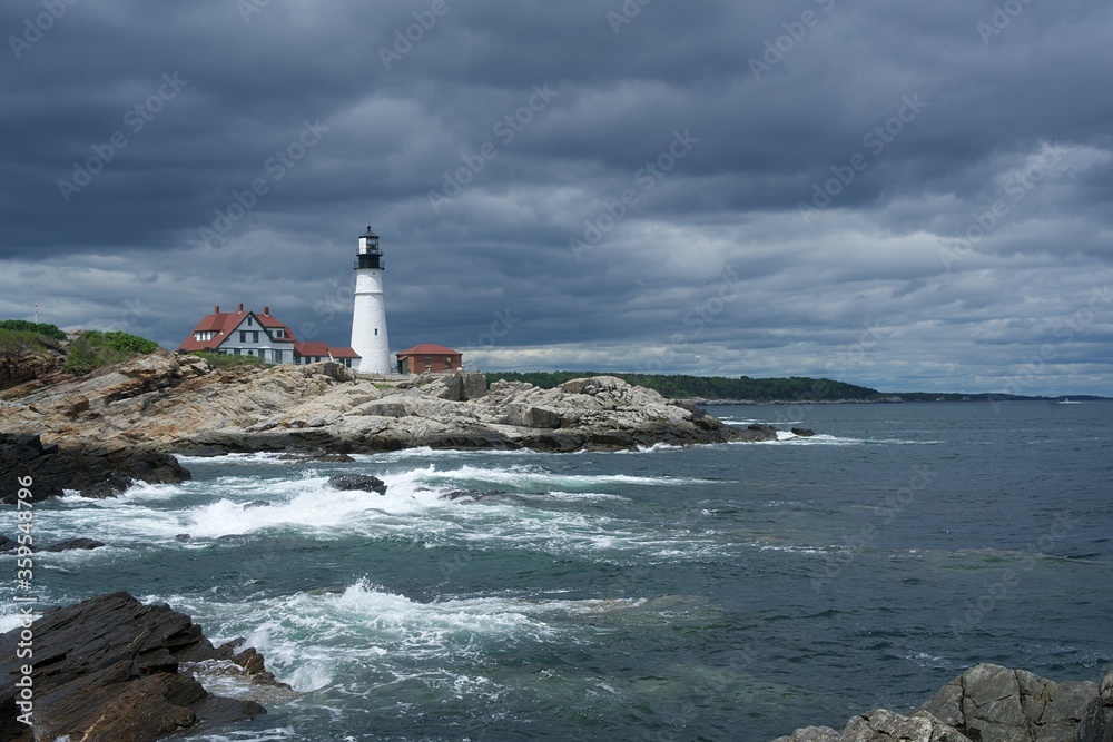 Portland Head Light Lighthouse in Maine under dark clouds and crashing waves