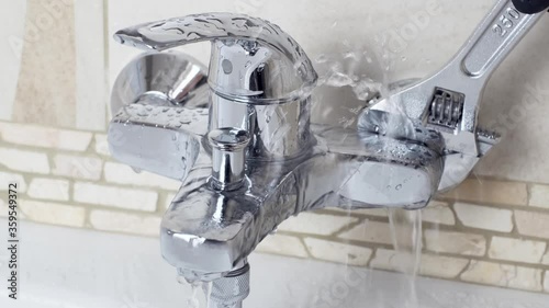 Plumber Fixing a water leaking tap Faucet by Adjustable wrench , DIY job house bathroom shower keep work fix leak repair.