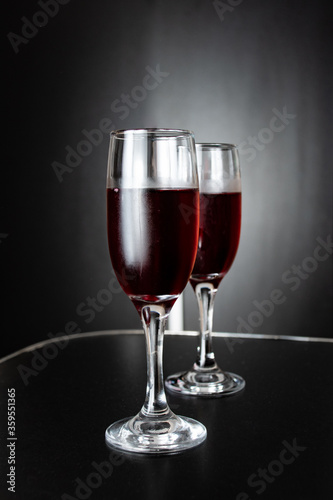 Two glasses of freshly poured red wine on black background