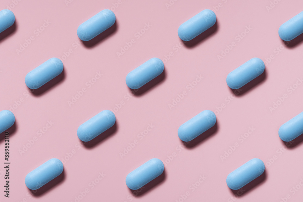 blue pills or capsules lie in rows diagonal on pink background top view pattern blue pills or capsules lie in rows diagonal on pink background top view pattern