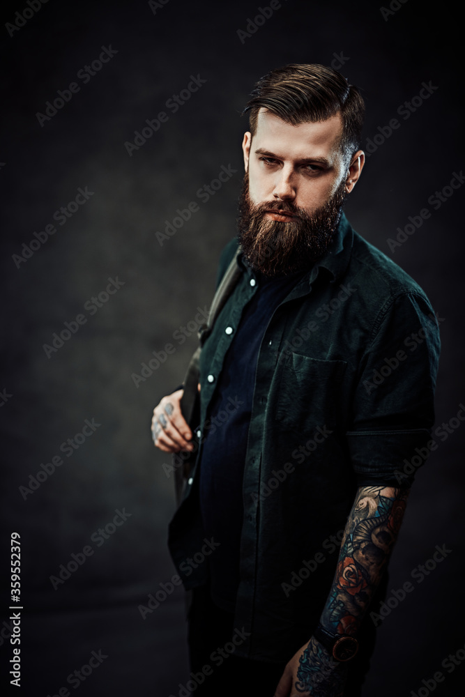 Obraz premium Young bearded hipster guy with backpack in dark studio