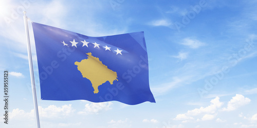 Kosovo flag on a flagpole waving in blue cloudy sky. Kosovo concept 3D rendering
