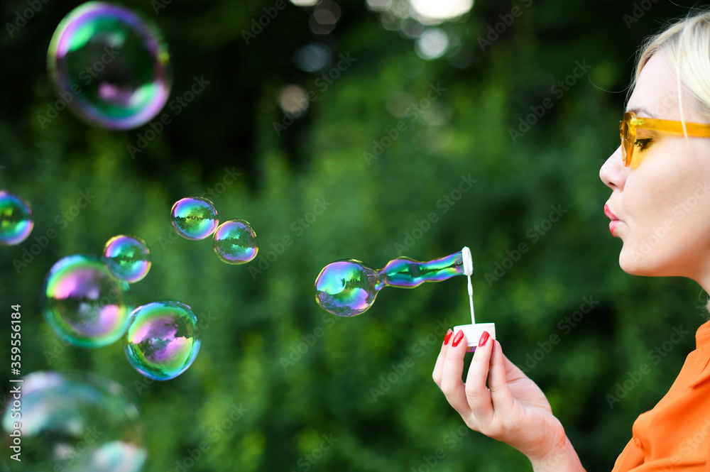 Beautiful girl blowing soap bubbles in park Beautiful girl blowing soap bubbles in park