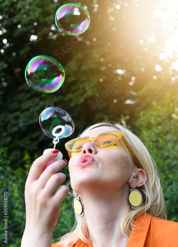 Beautiful girl blowing soap bubbles in park