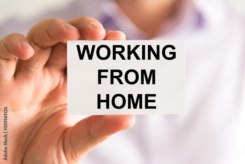 Businessman holding Working From Home message card Businessman holding Working From Home message card
