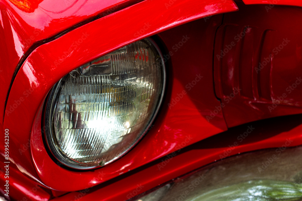 Front round headlight of a red retro car. Detail of an old vintage car. Modern tuning. High quality photo