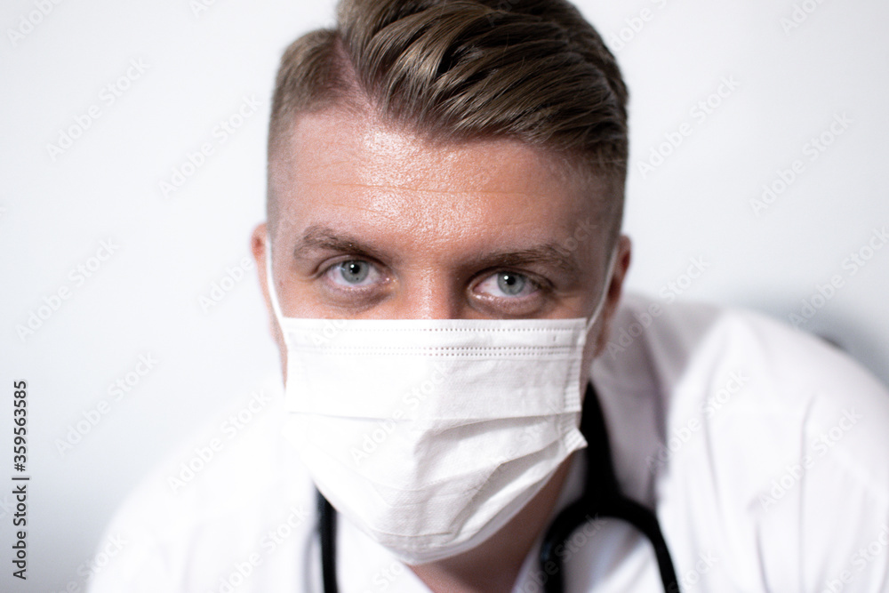 Portrait of smiling young caucasian male doctor wear white medical uniform, stethoscope and mask Portrait of smiling young caucasian male doctor wear white medical uniform, stethoscope and mask